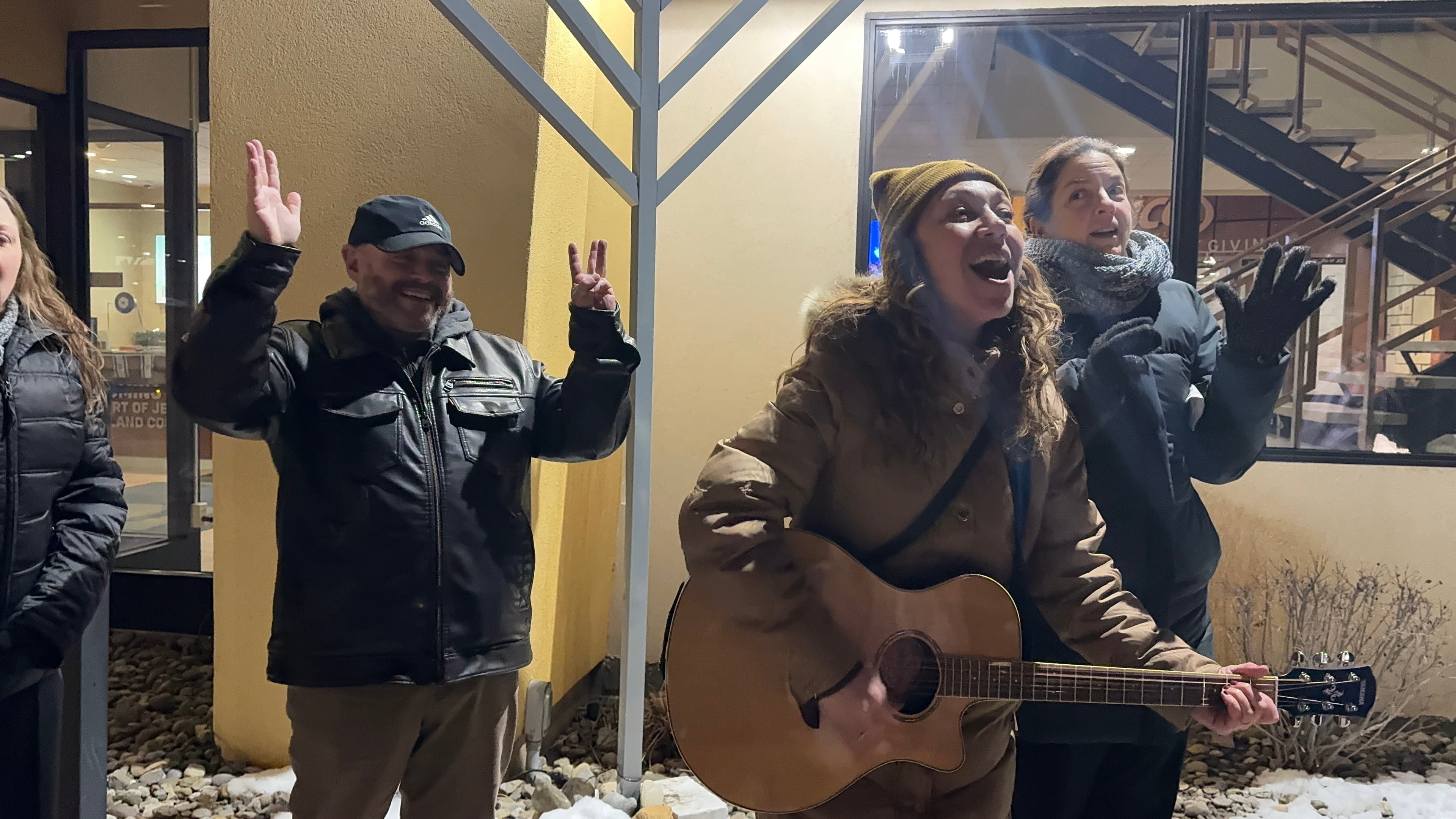 Cantor Anna singing joyfully at the outdoor Hanukkah menorah lighting celebration